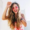 A woman wearing sunglasses and headphones, smiling at the camera. Produktbild-Vorschau