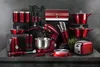 A collection of red kitchen appliances and cookware arranged on a dark surface against a textured gray background. Náhled obrázku produktu