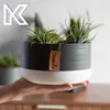 A hand holding a ceramic planter with plants inside. Podgląd zdjęcia produktu