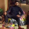 A man is sitting on a colorful bean bag chair with a matching ottoman in a modern indoor setting. Voir les images du produit
