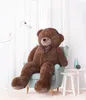 A large brown teddy bear sits in a light blue armchair next to a floor lamp and a small white side table with vases. Voir les images du produit