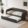 A gray upholstered daybed with a pull-out trundle bed, set up in a room with a plant and a framed picture on the wall. Anteprima dell’immagine prodotto