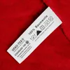 A close-up of a clothing care label on a red fabric. Produktbild-Vorschau