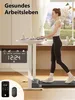 A woman is walking on a treadmill desk while working on a laptop. A digital display shows time, distance, speed, and calories. A smartphone and remote control are also shown. Produktbild-Vorschau