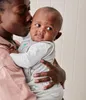 A person is holding and kissing a baby who is wearing a swaddle. Produktbild-Vorschau