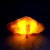 A glowing croissant-shaped lamp sits on a dark, reflective surface. Podgląd zdjęcia produktu