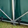 Close-up view of the metal frame and green PVC tarp of a storage tent or shelter. Voir les images du produit