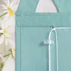 A close-up of a green fabric blind with white strings and a clear plastic fastener, with daisies in the background. Produktbild-Vorschau