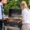 A man and a woman are grilling food outdoors. Produktbild-Vorschau