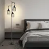 A bedroom scene with a floor lamp next to a bed. Podgląd zdjęcia produktu