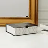 A decorative box sits on a marble surface in front of a large ornate gold mirror. Produktbild-Vorschau