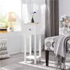 A white wooden nightstand with a drawer and two shelves is shown next to a chair with a patterned upholstery. A lamp and books are on a windowsill in the background. Produktbild-Vorschau