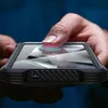 A close-up shot of a person's finger using a fingerprint scanner on a smartphone. Produktbild-Vorschau