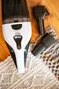 A close-up shot of a cordless vacuum cleaner and its accessories on a wooden floor and a textured rug. Anteprima dell’immagine prodotto