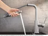 A hand is holding a pull-out spray faucet, with water spraying out. Produktbild-Vorschau