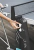 A person's hand is shown placing ping pong balls into a holder on the side of an outdoor table tennis table. Produktbild-Vorschau