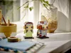 Two LEGO BrickHeadz figures, Aragorn and Arwen, are displayed on a white surface next to a ceramic cup with pens and a roll of tape. Produktbild-Vorschau
