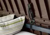 Close-up of the interior of a brown storage box, showing a gas strut mechanism and striped cushions. Podgląd zdjęcia produktu