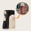 A product shot of a baby bottle warmer and its accessory pouch, with a close-up inset showing the warmer in use with a bottle. Produktbild-Vorschau