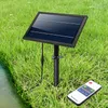 A solar panel and remote control are placed in the grass near a body of water. Podgląd zdjęcia produktu