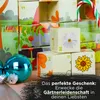 A close-up of an advent calendar with small boxes, some decorated with flowers and numbers, and Christmas ornaments in the foreground. Produktbild-Vorschau