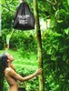 A woman is showering outdoors in a lush green environment, with a black solar shower bag hanging from a tree. Podgląd zdjęcia produktu