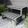 A grey outdoor hot tub step is shown next to a grey wall and some green plants. Podgląd zdjęcia produktu