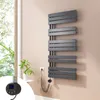 A modern anthracite electric towel radiator mounted on a light beige wall next to a window with greenery visible outside. Voir les images du produit