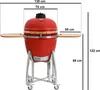 A red ceramic kamado grill on a silver stand with wooden side tables, with dimensions indicated by lines and text. Produktbild-Vorschau