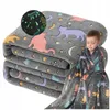 A child wrapped in a glow-in-the-dark cat-themed blanket, with a folded stack of the same blankets in the background. Náhled obrázku produktu