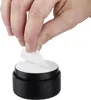 A hand is peeling a white sticker from a black cylindrical object. Produktbild-Vorschau