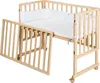 A wooden crib with a white mattress and bumper pad, shown with one side panel open. Produktbild-Vorschau