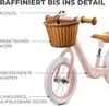 Close-up of a pink balance bike with a basket and labels pointing out its features. Produktbild-Vorschau