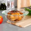 A roasted chicken in a glass baking dish on a wooden cutting board, with an apple and parsley in the background. Podgląd zdjęcia produktu