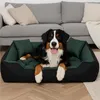 A Bernese Mountain Dog is lying comfortably in a green and black dog bed in a living room setting. Voir les images du produit