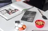 A kitchen counter with a cookbook, a digital scale, eggs, walnuts, and a spatula. Voir les images du produit