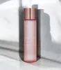 A pink bottle of toner with a rose gold cap, standing upright against a light gray wall with shadows. Náhled obrázku produktu