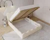A beige upholstered bed with its mattress lifted to reveal storage space underneath. Náhled obrázku produktu