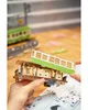 A person's hands assembling a wooden model train car. Produktbild-Vorschau
