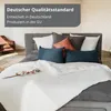 A bed with pillows and a duvet, with a text overlay. Produktbild-Vorschau