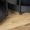 A close-up view of the bottom of two black metal plant stands resting on a wooden floor. Produktbild-Vorschau