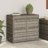 A poly rattan garden cabinet with two doors and a plant on top, placed on a tiled patio next to a wall. Voir les images du produit