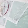 A close-up of a sheer curtain with embroidered details, layered over a magazine or printed material with text. Produktbild-Vorschau