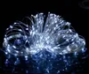 A coiled string of white LED lights on a black reflective surface. Voir les images du produit