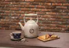 A cream-colored electric kettle is shown on a wooden table with a cup of tea and toast, set against a brick wall. Anteprima dell’immagine prodotto