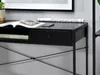 A close-up view of a black desk with a book, a rolled-up document, and a smartphone on its surface. Voir les images du produit