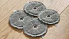 Four round gray cleaning pads with a hole in the center are arranged on a wooden floor. Voir les images du produit