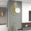 A wall clock with a wheat design is displayed on a gray wall in a modern living room setting. Produktbild-Vorschau
