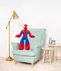 A Spider-Man plush toy sitting on a light blue armchair in a room with a floor lamp and side tables. Náhľad obrázku produktu