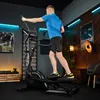 A man is exercising on a crosstrainer in a home gym setting. Produktbild-Vorschau